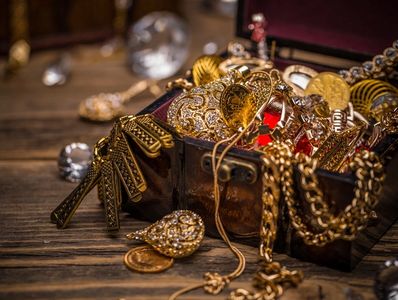 A treasure chest overflowing with gold jewelry and coins.