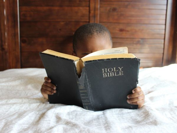 Little boy reading a bible