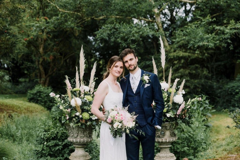 A bride and groom surrounded by white and green floral arrangements.