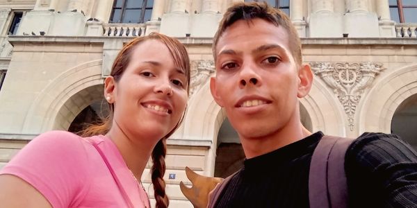 A smiling couple poses for a selfie in front of a historic building.