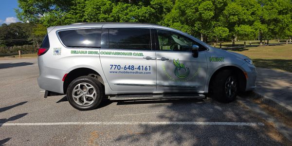 Silver van with medical transport branding parked in a lot.