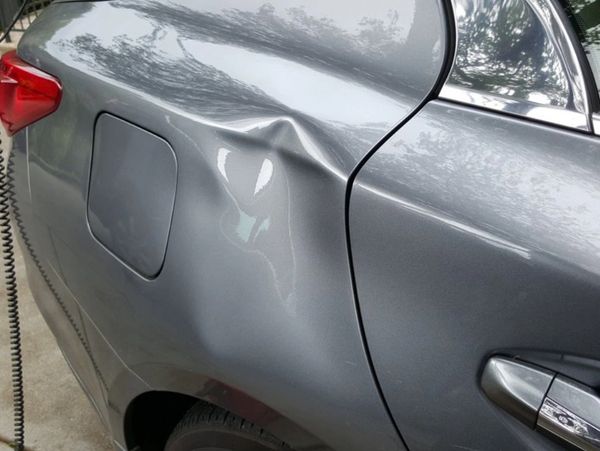 Large complex dent on a quarter panel of a vehicle.
