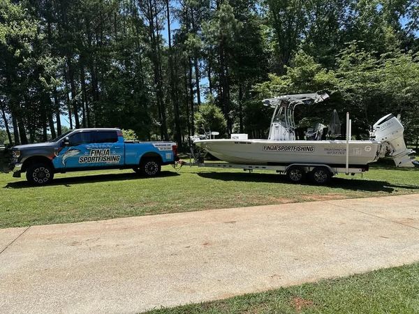 Truck towing a boat labeled Finja Sportfishing.