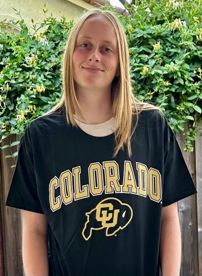 Young woman wearing a black Colorado t-shirt, smiling outdoors.