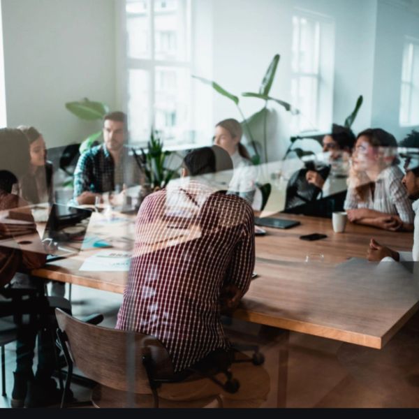 A group of people in a meeting around a wooden table in a bright office.