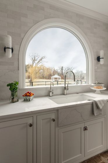 Elegant kitchen sink area with a large arched window overlooking a peaceful garden.