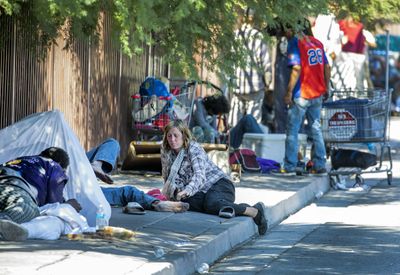 People resting and sitting on a sidewalk in an urban setting.
