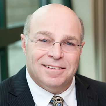 Smiling bald man in glasses and suit.