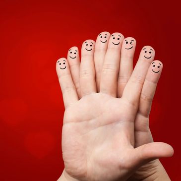 Smiling faces drawn on fingertips against a red background.