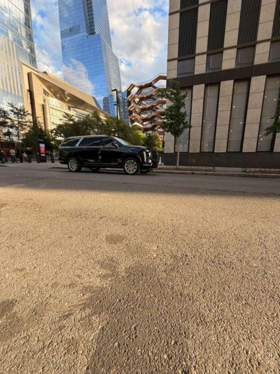 Black SUV parked on a city street with modern buildings.
