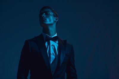 Man in a tuxedo with dramatic blue lighting.