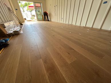 New wooden floor being installed in a bright room with large windows.