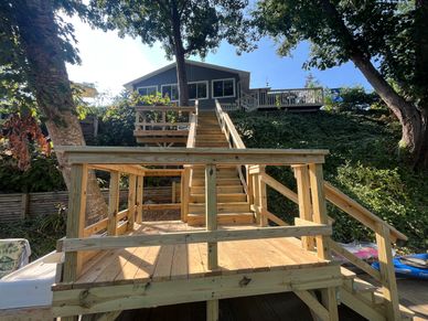 A wooden stairway and deck leading up to a house on a hill.