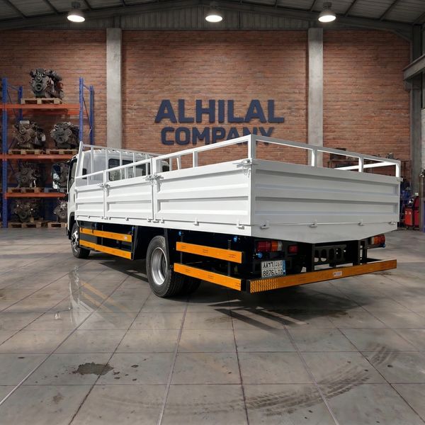 White flatbed truck parked inside a warehouse with ALHILAL COMPANY sign.