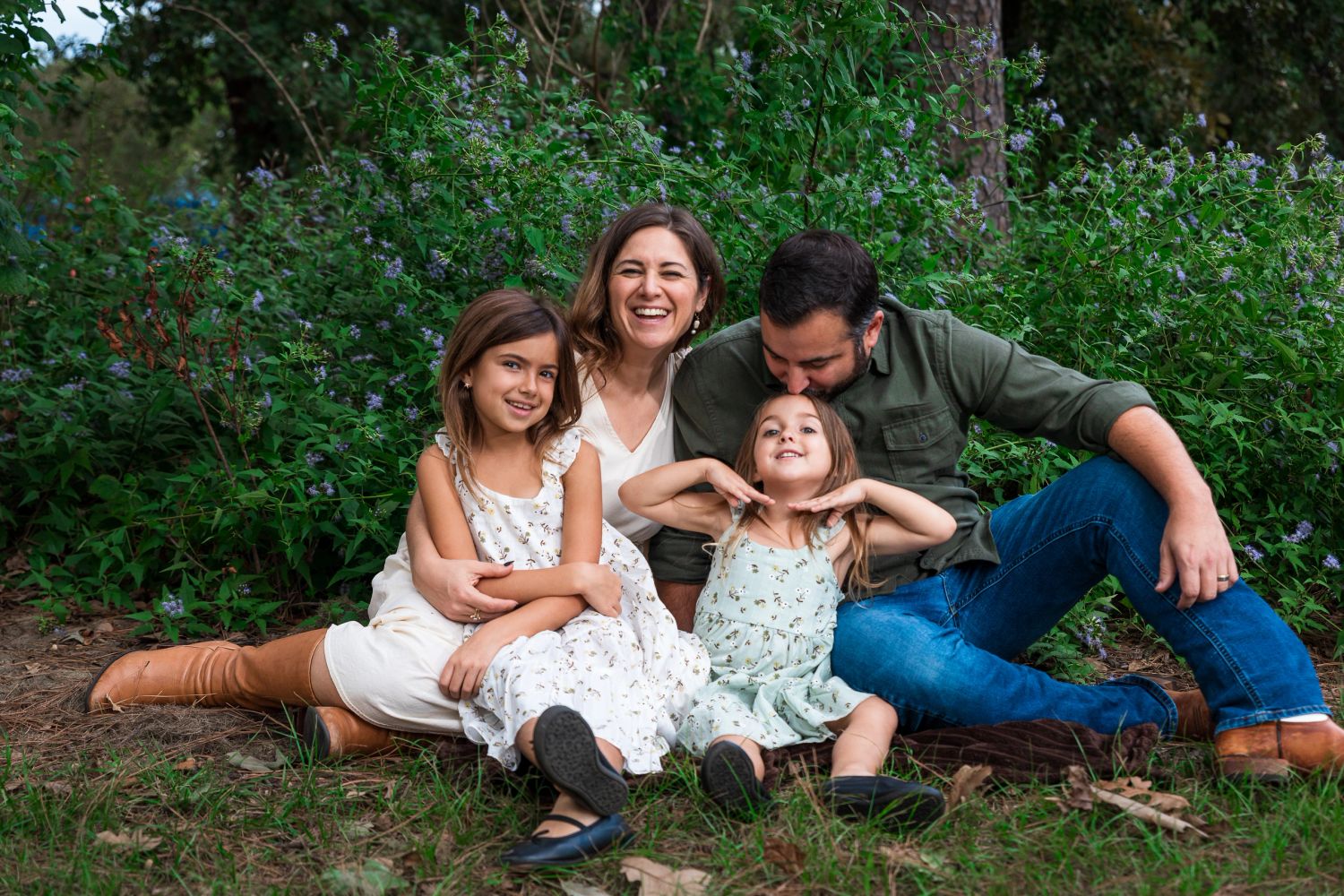 Smiling family sitting together in a natural setting during a family portrait session in Austin