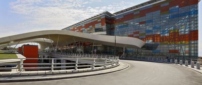 Modern building with colorful glass facade and curved walkway.