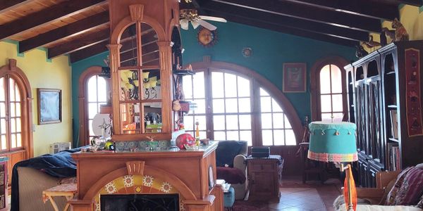 Cozy living room with wooden beams, colorful walls, and large arched windows letting in natural light.