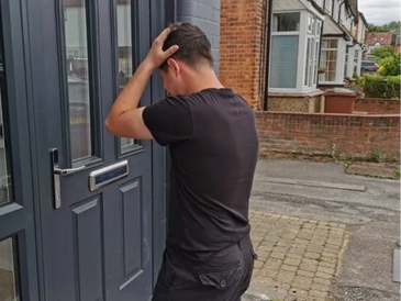 Man standing outside a door, holding his head in frustration.
