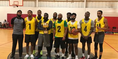 Basketball team posing with a trophy in an indoor court.