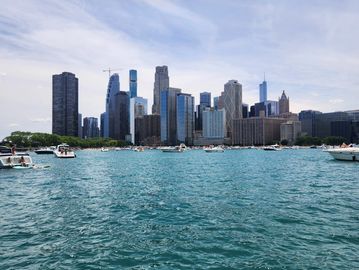 City skyline with boats on a large body of water under a bright sky.