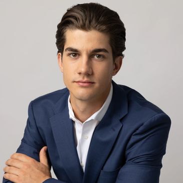 Young man in a blue suit posing confidently against a plain background.