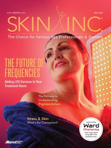 Skin cover for month of May 2023. A woman looking away smiling and red LED shinning behind her 