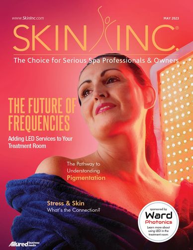 Skin cover for month of May 2023. A woman looking away smiling and red LED shinning behind her 