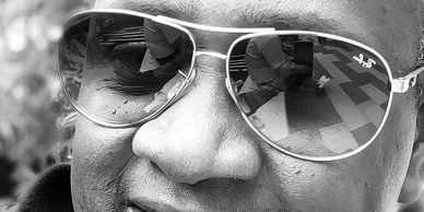 Close-up of a smiling person wearing reflective aviator sunglasses.