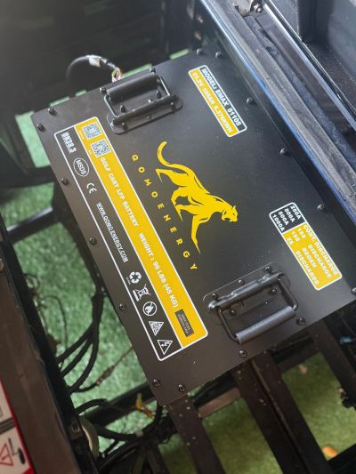 Close-up of a black battery box with yellow branding and safety labels.