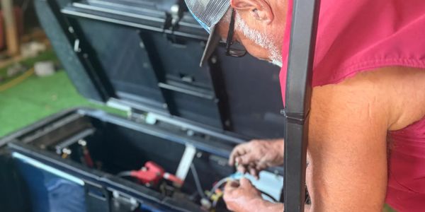 A man repairs equipment inside a large black case.