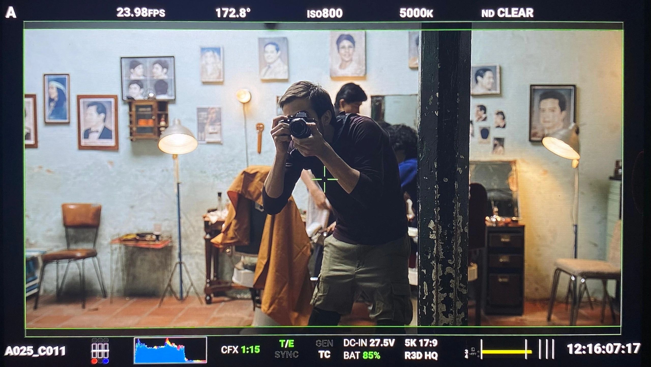 Man taking photo in a vintage room filled with portraits and warm lighting.