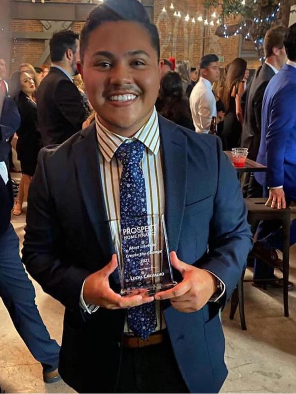 Smiling man in suit holding an award at a formal event.
