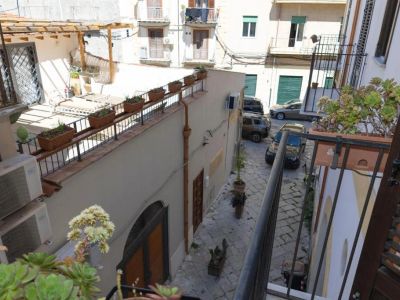 A narrow courtyard with potted plants and parked cars in a residential area.