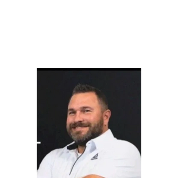 Smiling man with beard and white shirt against black background.