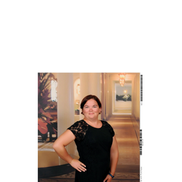 Woman in a black dress posing indoors with a confident smile.