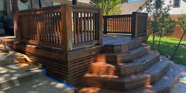 Newly stained wooden deck with multi-level steps and railing.