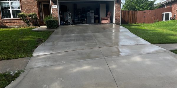 A clean, freshly washed driveway leading to an open garage with various items inside.
