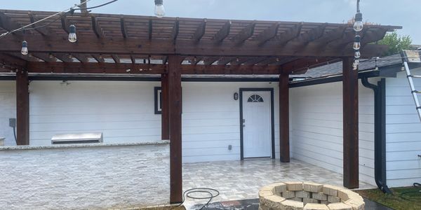 Backyard patio with pergola, string lights, fire pit, and grill area.

Exterior Wood Restoration & Pergola Staining