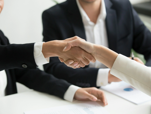 Two businesspeople shaking hands over a table.