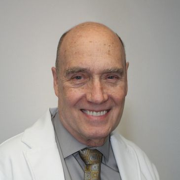 Smiling older man in a white coat.