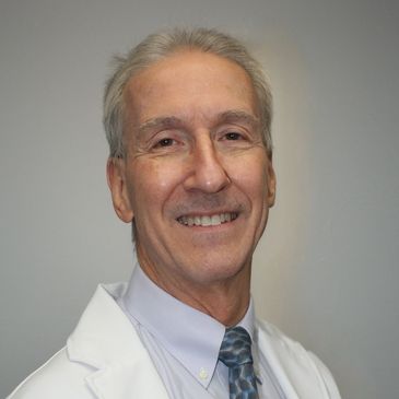 Smiling elderly man in white coat.