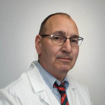Portrait of a middle-aged male doctor wearing glasses and a white coat.