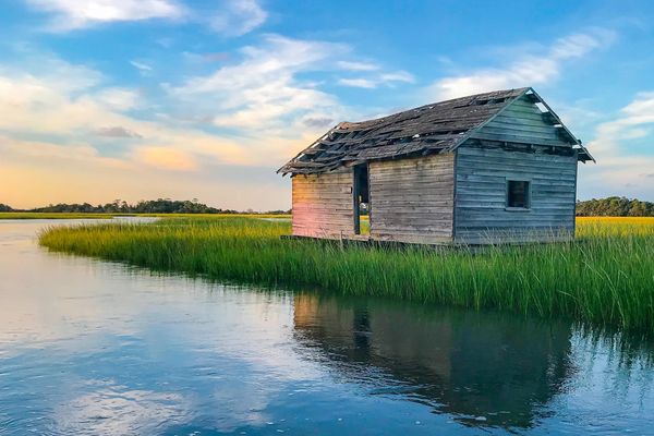 Old wooden boat house reflection in marsh creek 