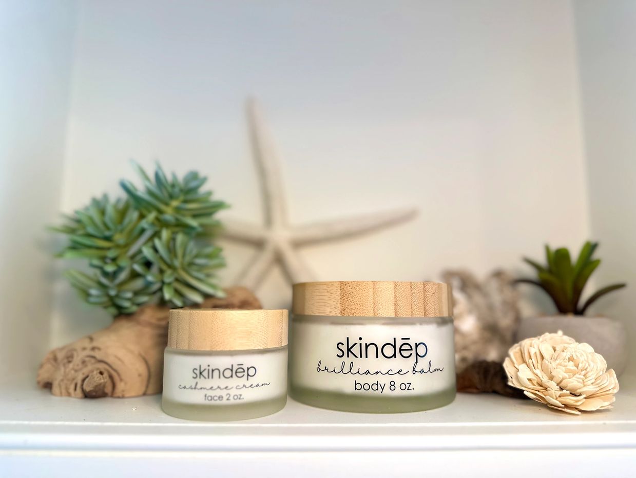 Skindēp skincare creams with natural decor on a white shelf.