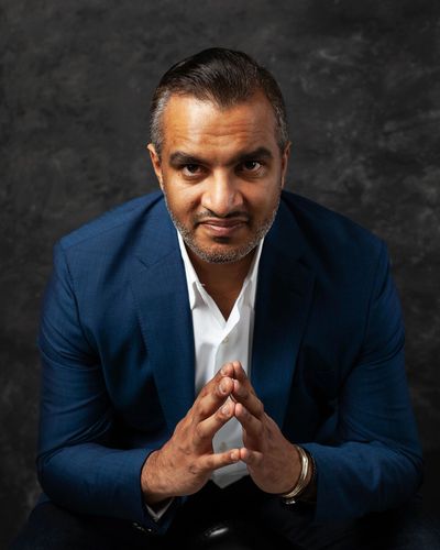 Confident man in blue suit with hands together.