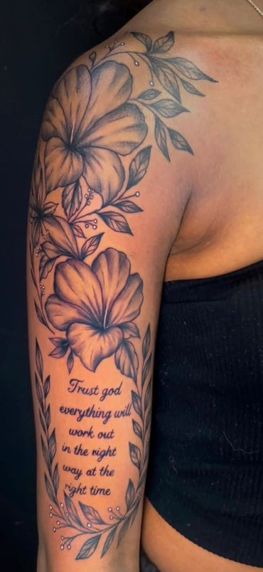 Floral tattoo with an inspirational quote on the arm.