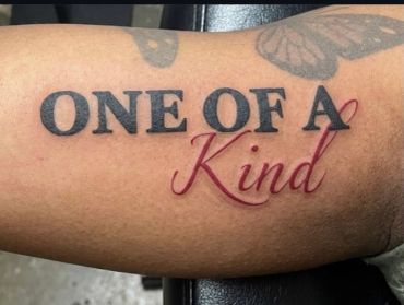 Tattoo saying 'ONE OF A Kind' with butterfly design.
