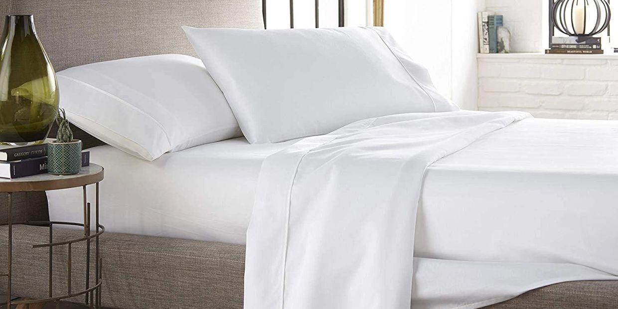 A neatly made bed with crisp white sheets and pillows in a modern bedroom.