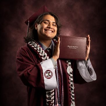 Graduate smiling with diploma and gown.
