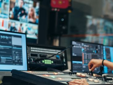 Person operating a sound mixing board in a control room.